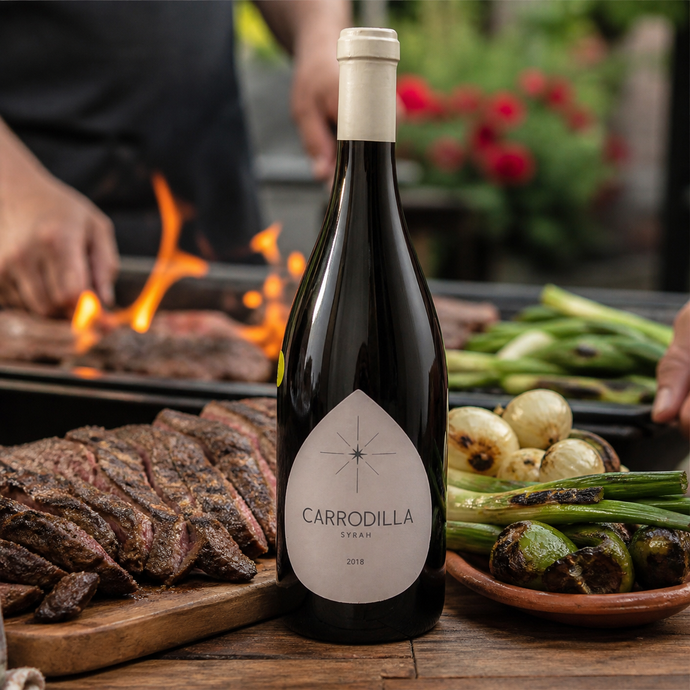 Botella de Carrodilla Syrah junto a carne y vegetales a la parrilla