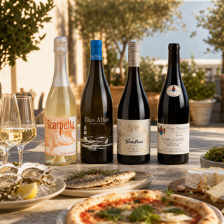 Cuatro botellas del Club de Vinos de agosto de 2025 en una mesa de verano